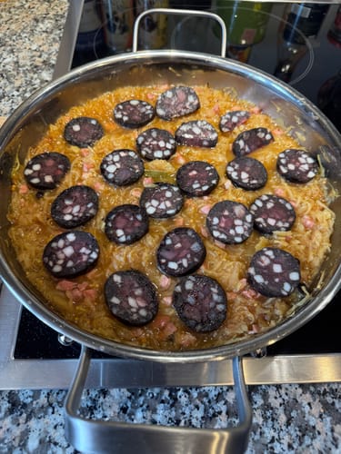 Rezensent kocht ein Gericht mit Wurst in der gehämmerten Titanpfanne auf einem Kochfeld.