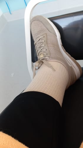 Kund som visar upp en beige Diasocks stödstrumpa på sitt ben, med en sko.