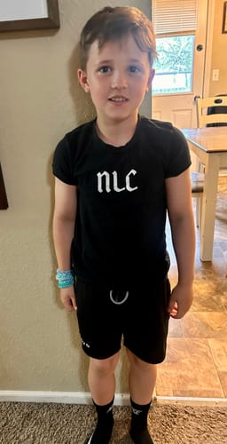 Customer's son wearing the black John 3:16 'The Cross' Youth Performance Shorts at home.