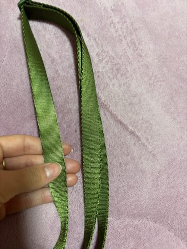 Mão de uma cliente mostrando a textura resistente da Alça Aurora na cor verde musgo.