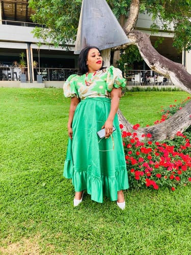Reviewer posing outdoors in the Ankara Puffy Sleeve Top and matching green midi skirt.