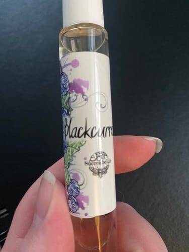 Reviewer holding the Blackcurrant perfume in a small rollerball bottle.