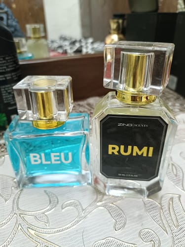 Customer's Bleu De Zing bottle with blue liquid next to the clear Rumi bottle with a black label.
