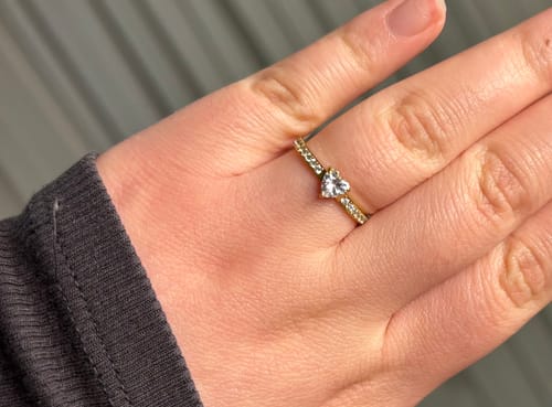 Die Hand eines Kunden, der den goldenen Herz Ring mit einem herzförmigen Stein trägt.