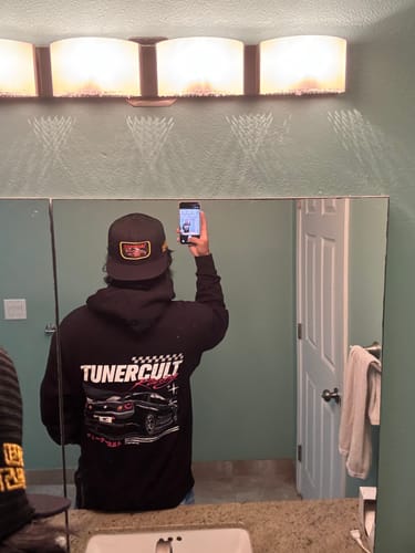 Reviewer seen from behind wearing the black SKYLINE TRUCKER HAT in a mirror selfie.