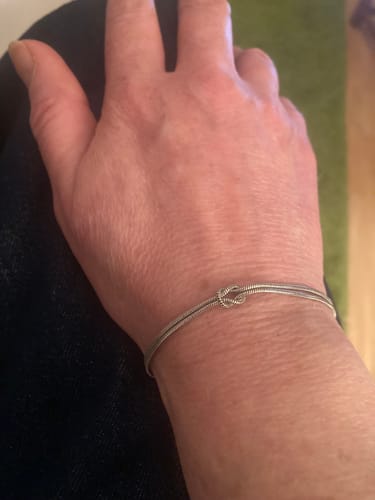 Close-up of a reviewer wearing the silver Forever Knot Bracelet on their wrist.