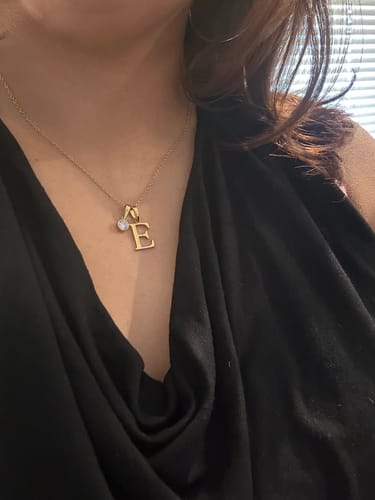Customer wearing the gold Birthstone Initial Necklace with an 'E' pendant and small birthstone.