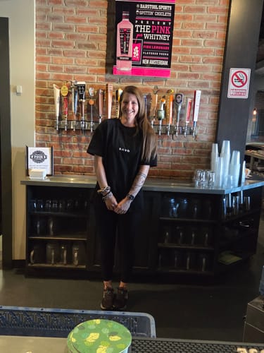 Customer wearing the black 'Warrior's Prayer' Oversized T-Shirt at work behind a bar.