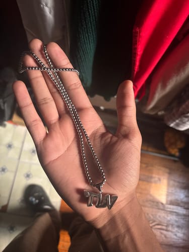 Customer's hand holding the silver-colored TLV CHAIN, showing the pendant and box-style chain.