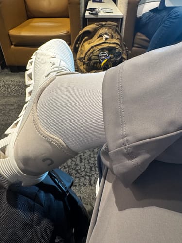 Reviewer resting at an airport wearing the white Performance Eucalyptus Compression Socks and a sneaker.