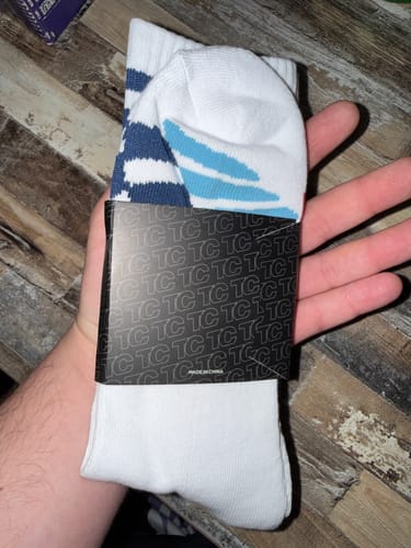 Reviewer holding a new pair of white M-POWER SOCKS with blue stripes in their packaging.