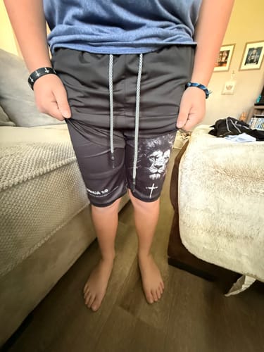 Customer wearing black Youth Performance Shorts with a lion graphic and 'Joshua 1:9' verse.