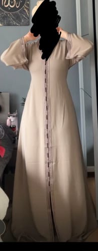 Reviewer wearing the light brown Dina kaftan, showing its flowing full-length fit and artisanal sfifa trim.