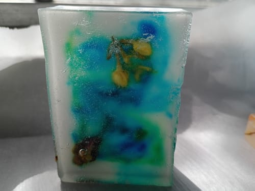 Customer's handmade soap bar with blue and green swirls and yellow flowers inside.