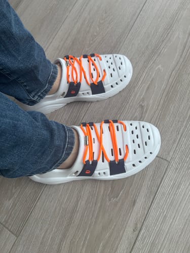 Customer wearing white Wildpool shoes with distinctive orange laces, seen from above.