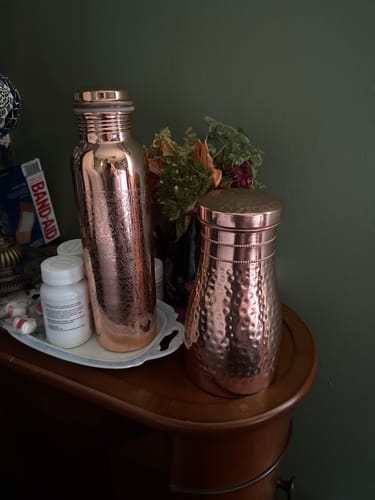 Customer's shiny Himalayan Ayurvedic Bedside Carafe with a hammered texture, placed on a wooden nightstand.