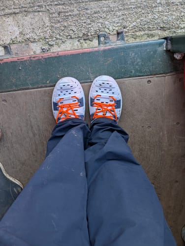 A reviewer's top-down view of the Early Bird Wildpools in Midnight Splash, showing the bright orange laces.