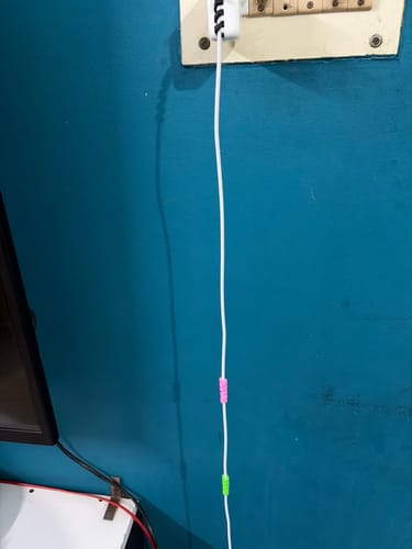 Customer's colorful cable protectors on a white wire plugged into a wall.