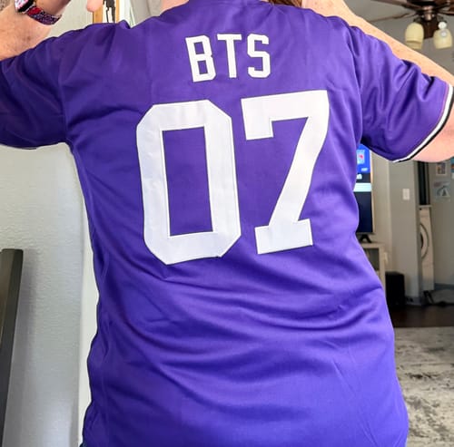 Reviewer showing the back of their purple custom baseball jersey with 'BTS' and the number '07'.