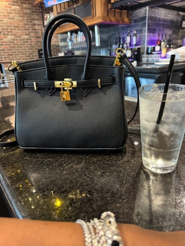 Customer's black pebbled Warkin Bag with gold hardware, shown on a restaurant counter.