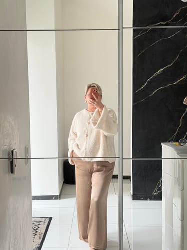Kundin trägt die locker sitzende, beigefarbene Satin Hose in einem Ganzkörperspiegel-Selfie.