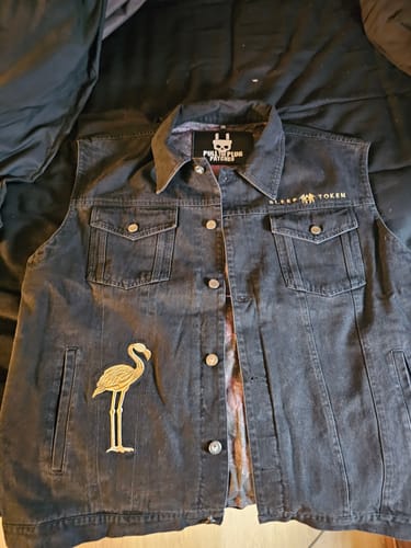 Customer's black denim Sleep Token vest laid flat, showing the front embroidery of a golden flamingo and the band name.