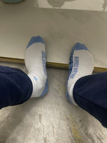 Customer wearing the white MOONSTONE CREW SOCKS with light blue details on a carpeted floor.