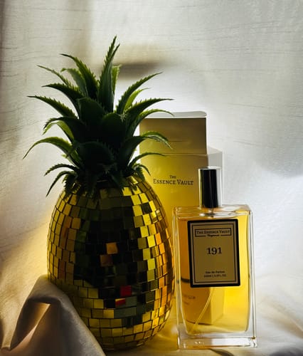 Customer's No. 191 perfume bottle and box, arranged next to a decorative golden pineapple.