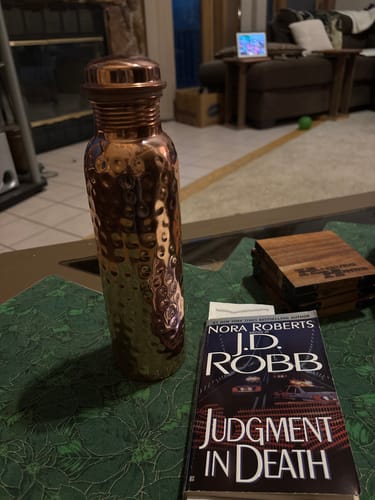 Reviewer's hammered copper bottle resting on a table next to a book.