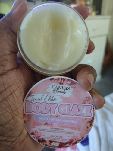 Customer holding an open jar of Travel Glaze Body Glaze, showing a dent from use and the separate pink lid.