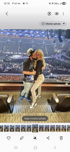 Reviewer posing with a partner at a concert, wearing acid-wash Golden High-Waisted Skinny Jeans.