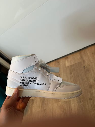 Recensent houdt een witte hoge sneaker in de hand, met tekst op de zijkant.
