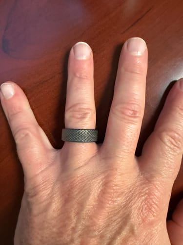 Customer's hand showing a dark textured ring that fits perfectly, after using the Thorum Ring Sizer.