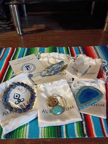 Customer's AuraBloom Subscription Box contents, including a blue agate slice, bracelet, and various crystals.