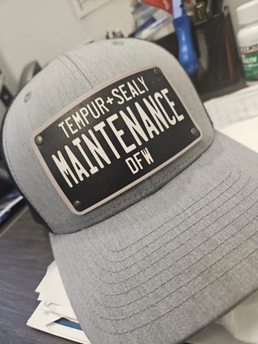Customer's grey Blackout Plate Hat with a custom license plate patch reading 'TEMPUR+SEALY MAINTENANCE DFW'.