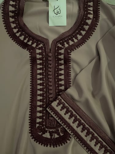 Close-up of the customer's mauve Kaftan Asya, showing the dark, detailed embroidery on the neckline and sleeve.