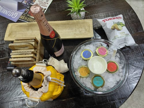 Reviewer's CAVI's Beginner Tasting Kit set up for a birthday with tins on ice, chips, and a bottle of champagne.