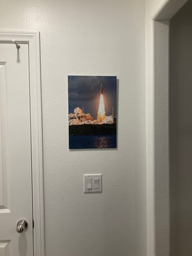 Customer's 'Full Send It! - SLS' print of a rocket launch hanging on a white wall.