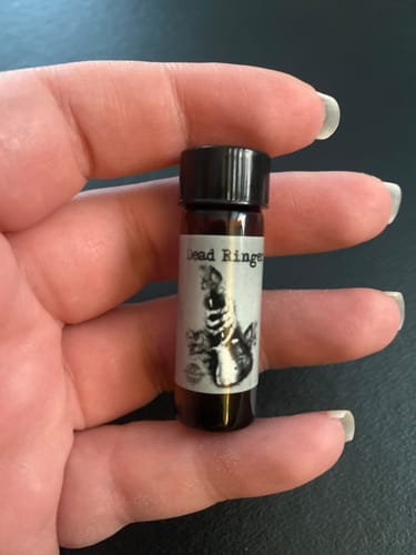 Reviewer holding a small vial of Dead Ringer scent oil in their hand.