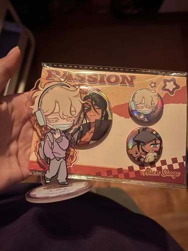 Customer holding the Alien Stage Luka acrylic stamp in front of its packaging, which also shows several character pins.