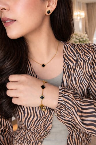 Customer wearing the Celine Clover Necklace with a single black clover pendant and gold-colored chain.