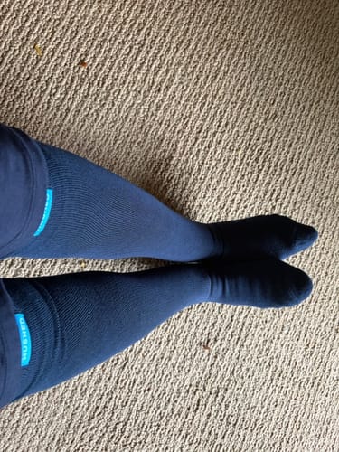 Customer's legs wearing navy Performance Eucalyptus Compression Socks on a carpeted floor.