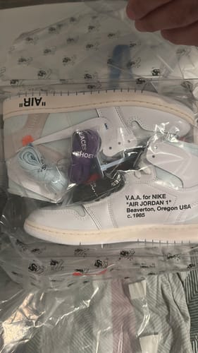 Recensent toont witte sneakers in de originele doorzichtige verpakking met extra veters.