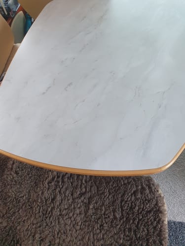 Kunde viser den hvite, matte marmorkontaktplasten lagt på en bordplate med trekanter.