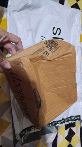 Customer showing the badly crushed and bent cardboard box from their Peptide Lip Glaze delivery.