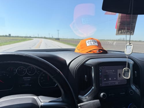 Reviewer's Hunter Orange Trucker Cap resting on the dashboard inside a truck.