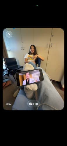 Reviewer smiling while seated and wearing the white sun and fun baby tee with jeans.