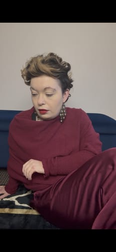 Customer sitting in the burgundy Belle Balloon Satin Trousers with a matching top.