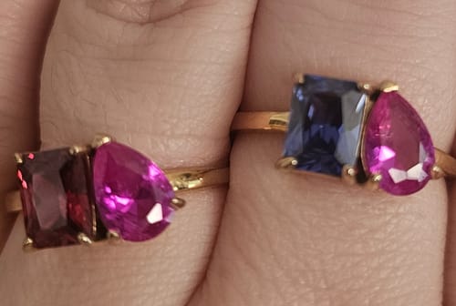 Close-up of a reviewer's hand wearing two Toi Et Moi Birthstone Rings with different colorful stone pairings.