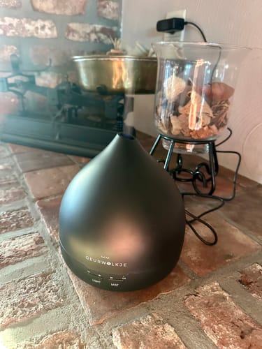 Close-up van de matzwarte Unity 2.0 diffuser van een klant, geplaatst op een bakstenen schouw.